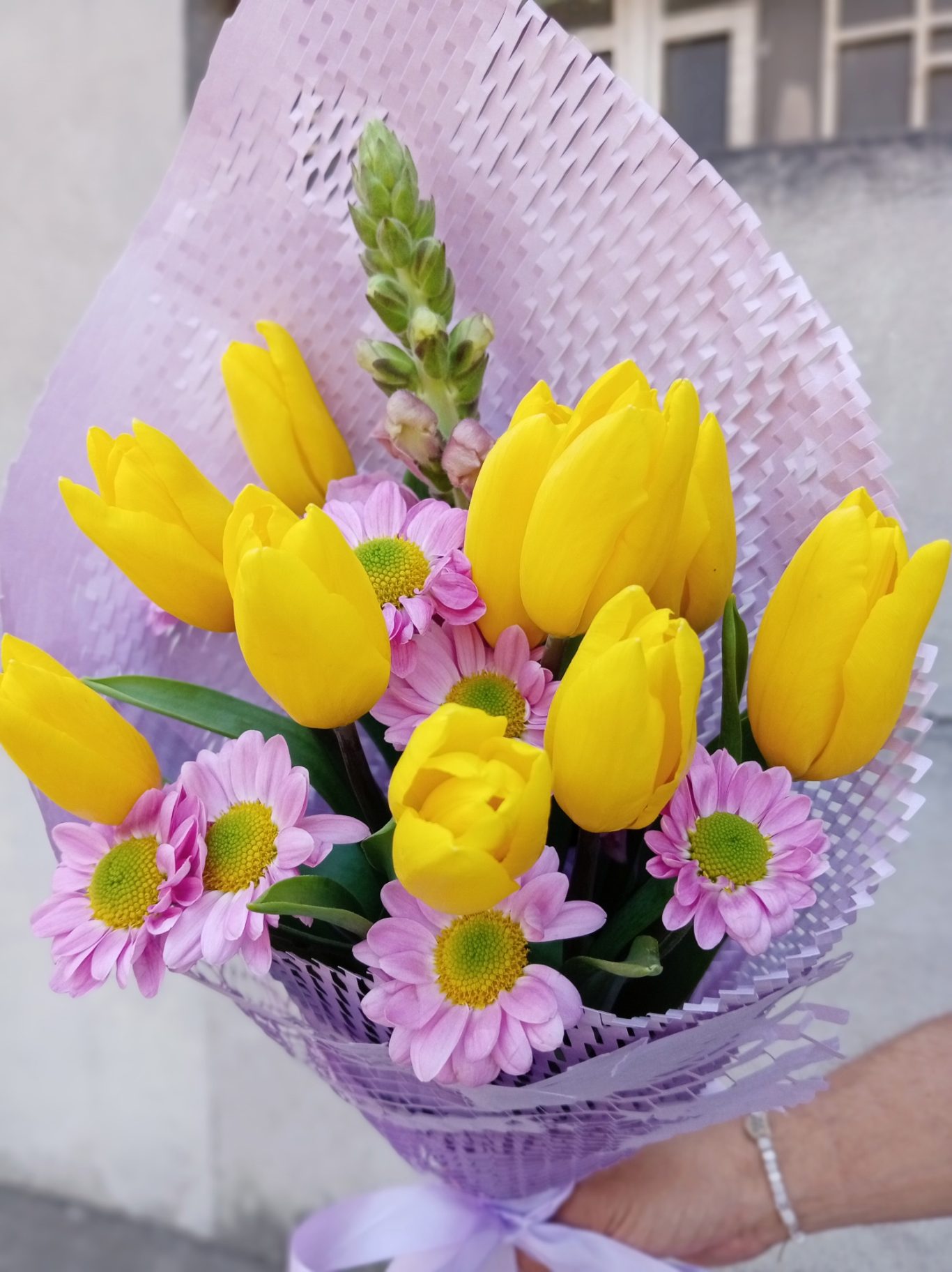 Ramo de flores con tulipanes amarillos y margaritas rosas.