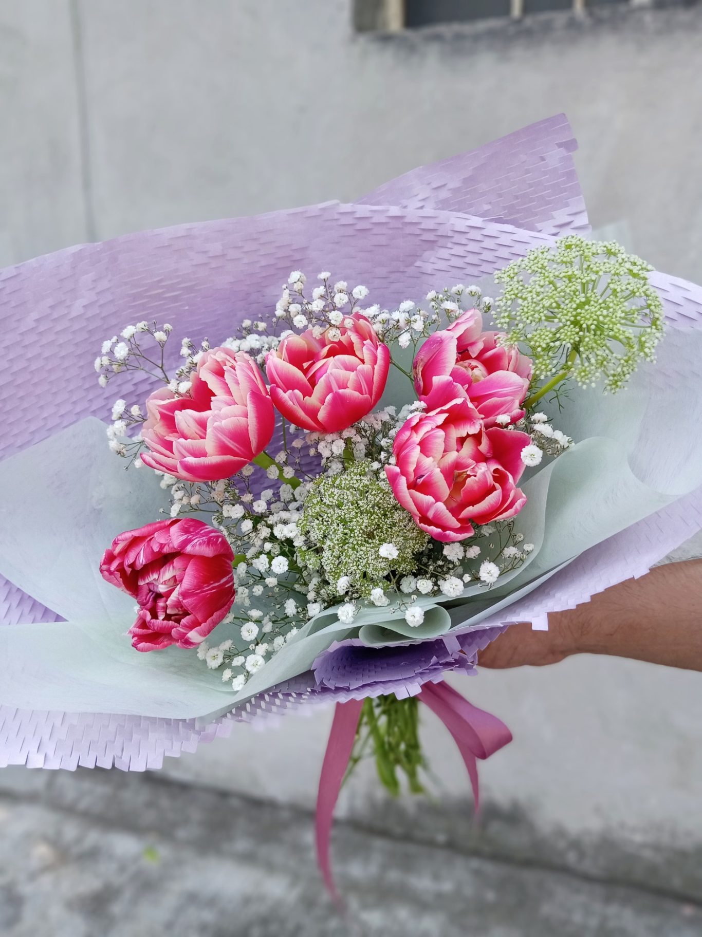 Ramo de flores con tulipanes rosas y verdes, envuelto en papel color lavanda.
