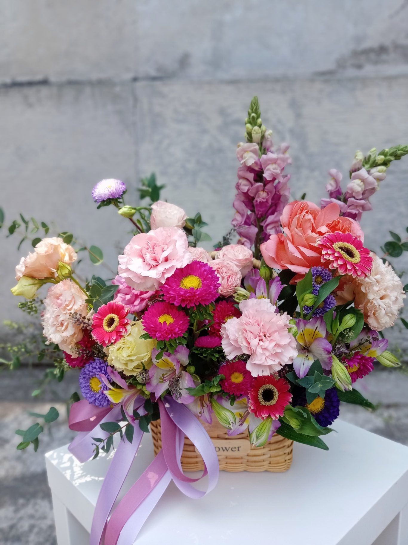 Ramo de flores coloridas en una canasta, con rosas, claveles y flores silvestres.