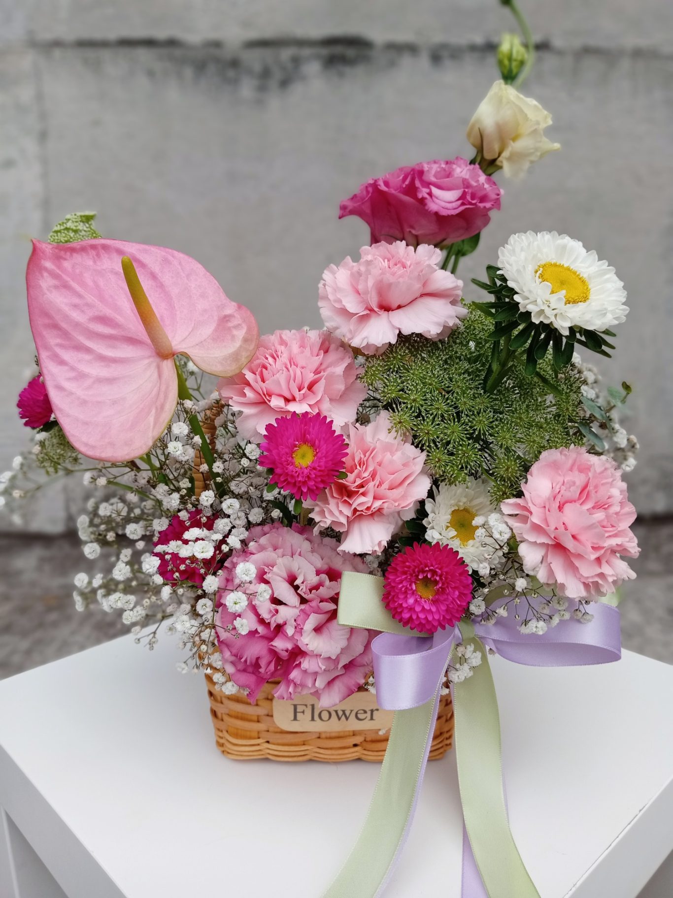 Ramo de flores variadas en una canasta, con tonos rosas, blancos y verdes.